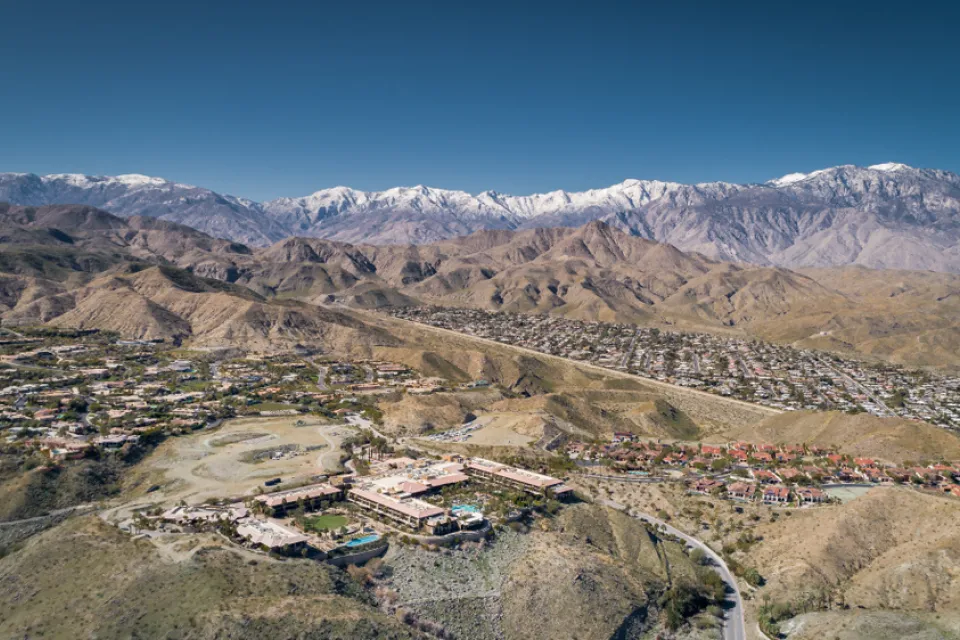 A large mansion is visible on a hill with the sprawling desert settlement of Rancho Mirage, California in the background.
